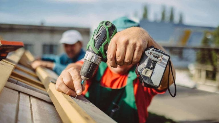 man using drill to install roof; best roofing contractors in falls church va