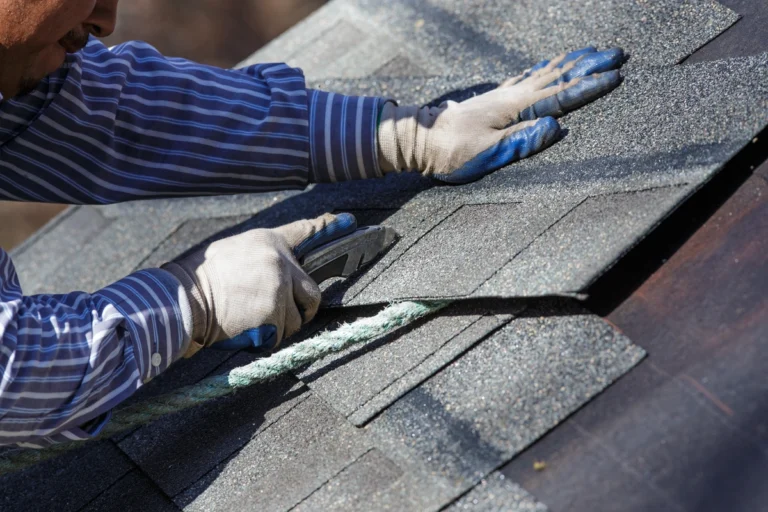contractor on roof cuts shingles after measuring