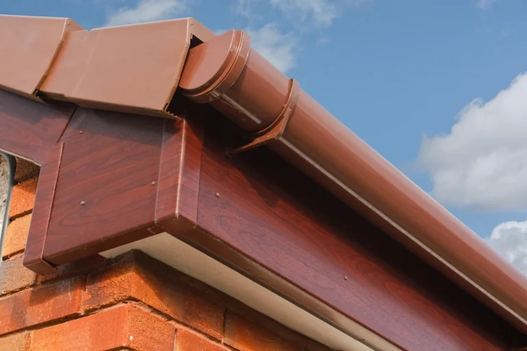 close up view of brick home with red roof fascia and metal gutters