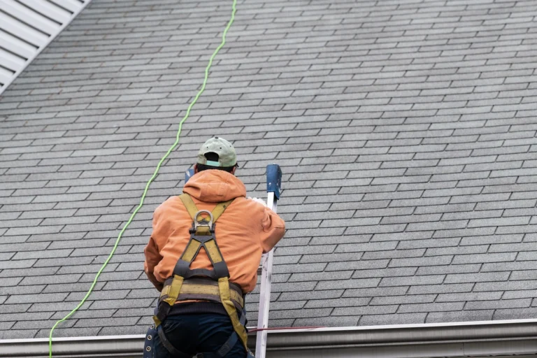 man inspecting the gray shingle roof