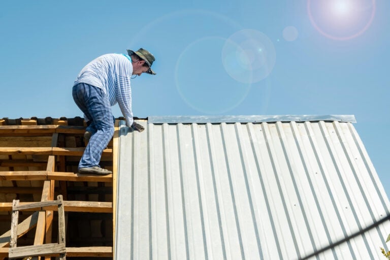 disadvantages of metal roofs-man installing metal panels on a house