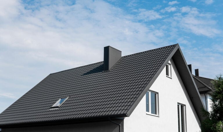 how long do metal roofs last-black metal shingles on a white house