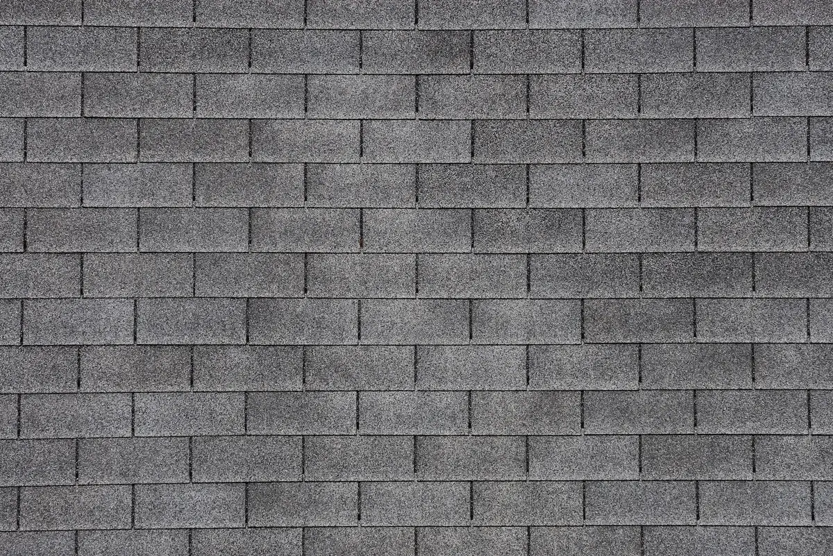 Close-up view of a gray asphalt shingle roof, showing a uniform pattern of rectangular shingles arranged in horizontal rows—ideal for learning how to replace missing shingles seamlessly.