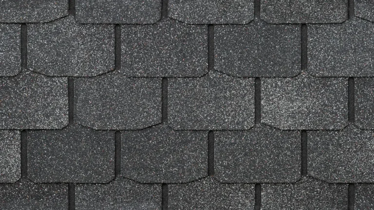 Close-up view of overlapping dark gray asphalt roof shingles with a rough, textured surface and hexagonal pattern—ideal for learning how to replace missing shingles efficiently.