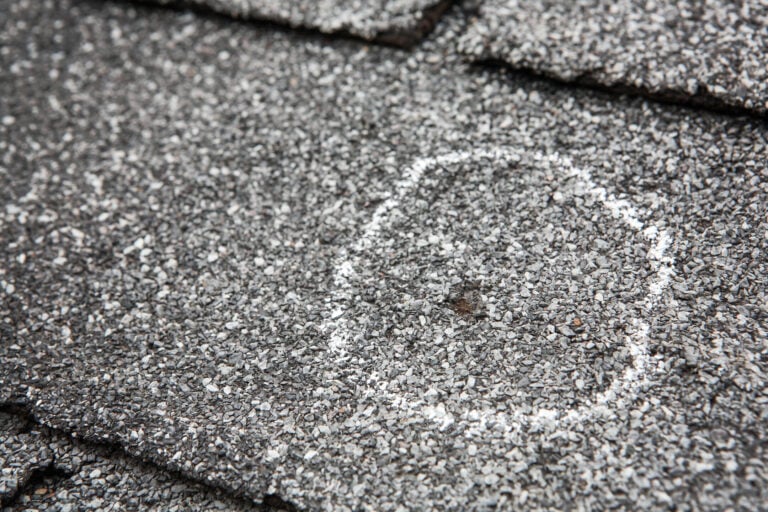 hail damage vs blistering-close up of hail damage circled in chalk on gray roof shingles