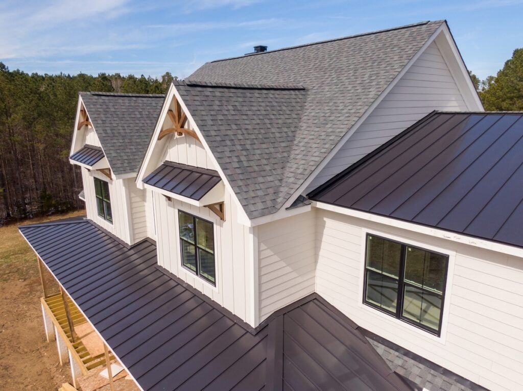 Sunny Daytime Drone Images of a Custom Home in the Final Stages of Construction. It Features a Roof With Architectural Asphalt Shingles and Standing Seam Accents.