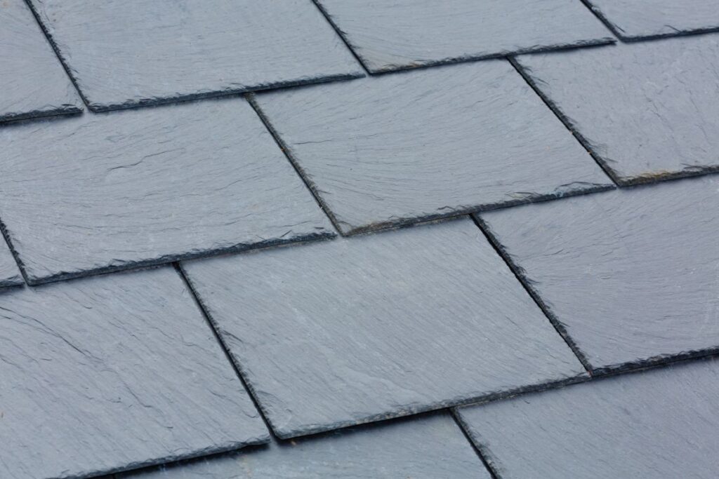 Close-up view of overlapping rectangular gray slate roof tiles, showing their textured surfaces and edges, ideal for premium roofing in Vienna VA.