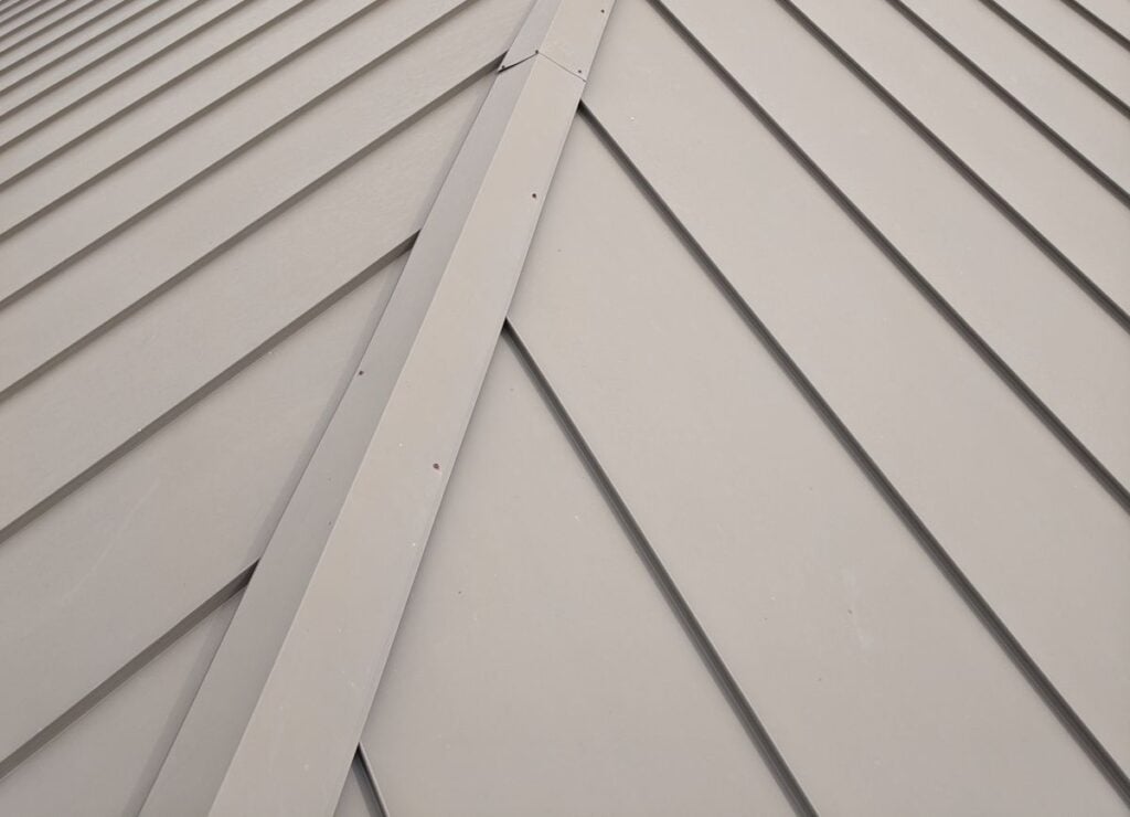 Close-up view of a gray metal roof with overlapping panels arranged in a diagonal pattern, creating a modern geometric design.