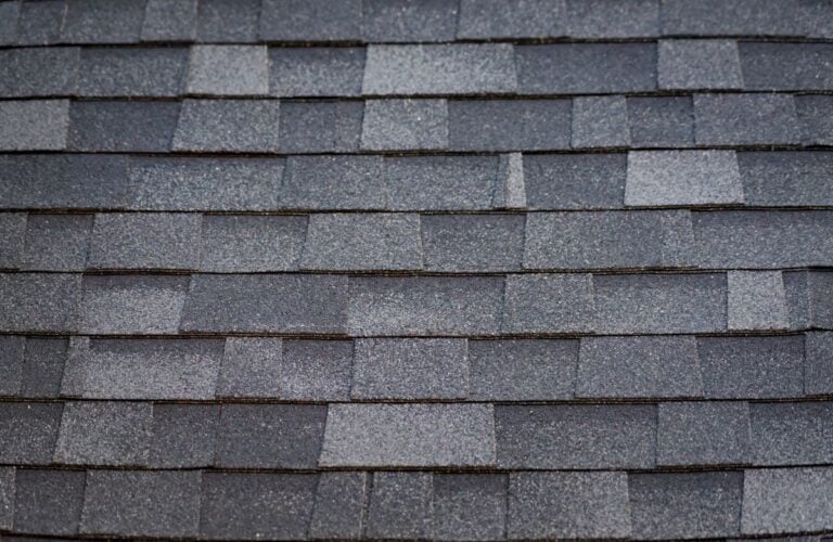 Close-up view of gray asphalt roof shingles arranged in even, overlapping rows with varying shades and textures.