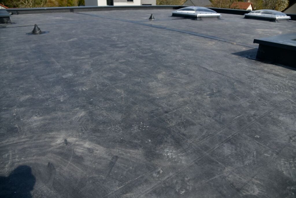A flat, dark gray EPDM roof featuring multiple skylights and several circular vents.