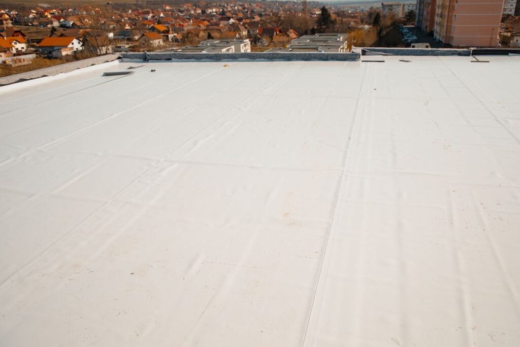 A wide, white flat roof surface overlooking a suburban neighborhood.