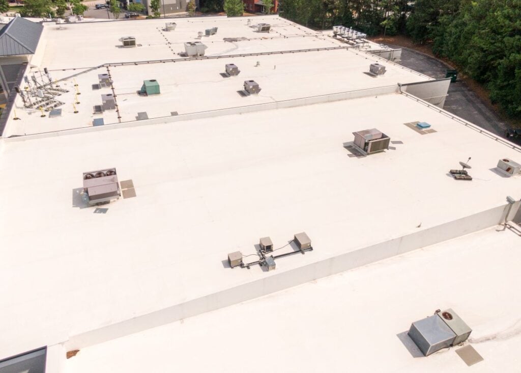 Aerial view of a flat commercial building roof with multiple HVAC units.